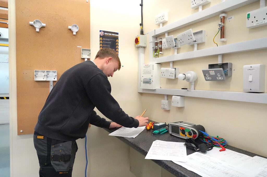 Electrician completing an EICR report on a inspection and testing course